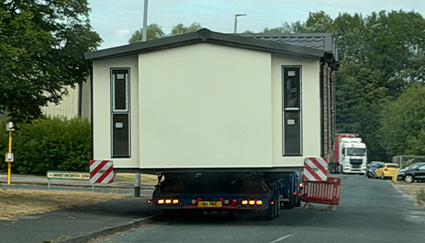 two mobile homes on trucks in a lot with cloudy sky portable living structures on the move