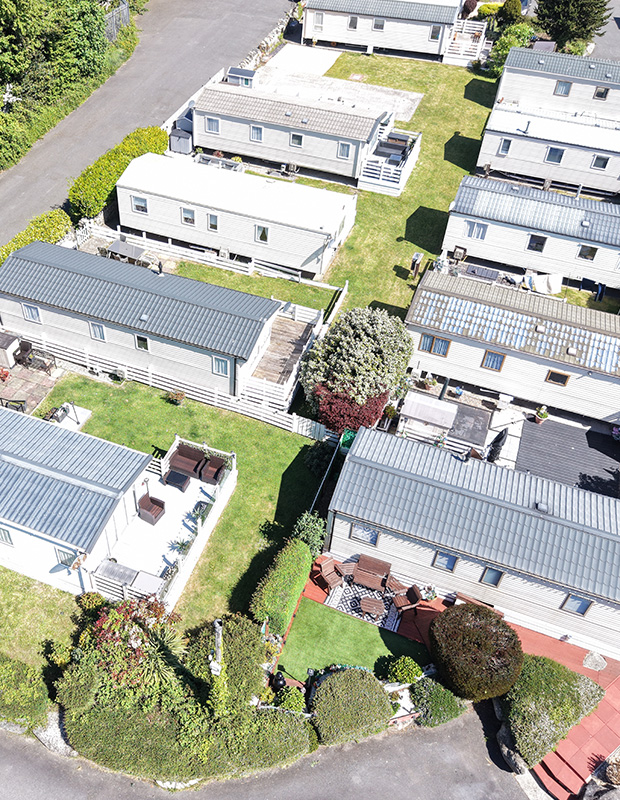 aerial view of several mobile homes and landscaped gardens in a recreational area featuring four distinct outdoor seating spaces and well-maintained green lawns